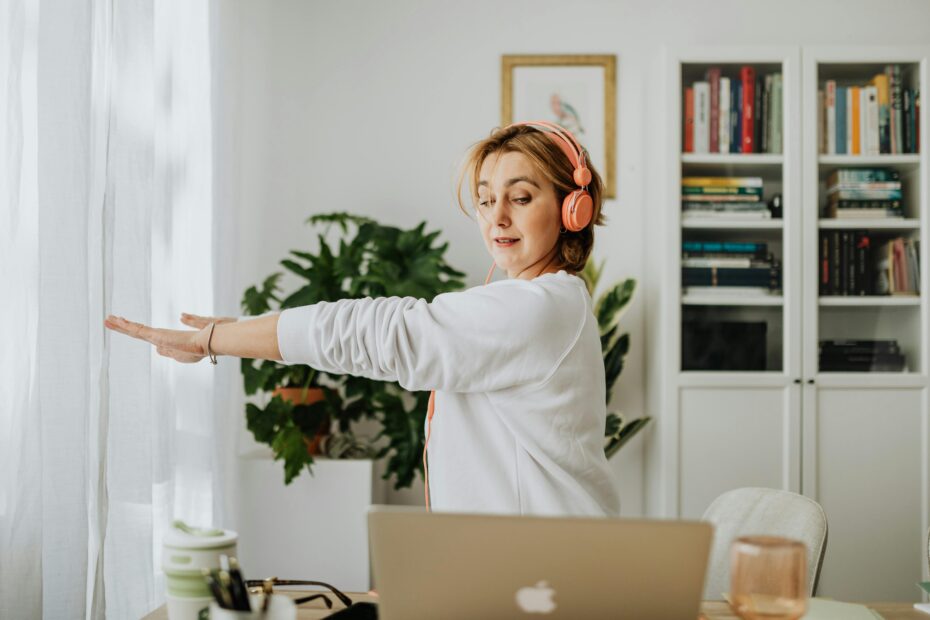 Woman exercising with headphones in a cozy home office setting. Lifestyle and wellness focus.